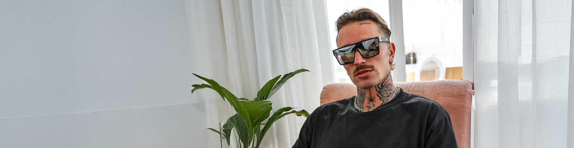 male model sitting by window wearing silver Loose Cannon sunglasses
