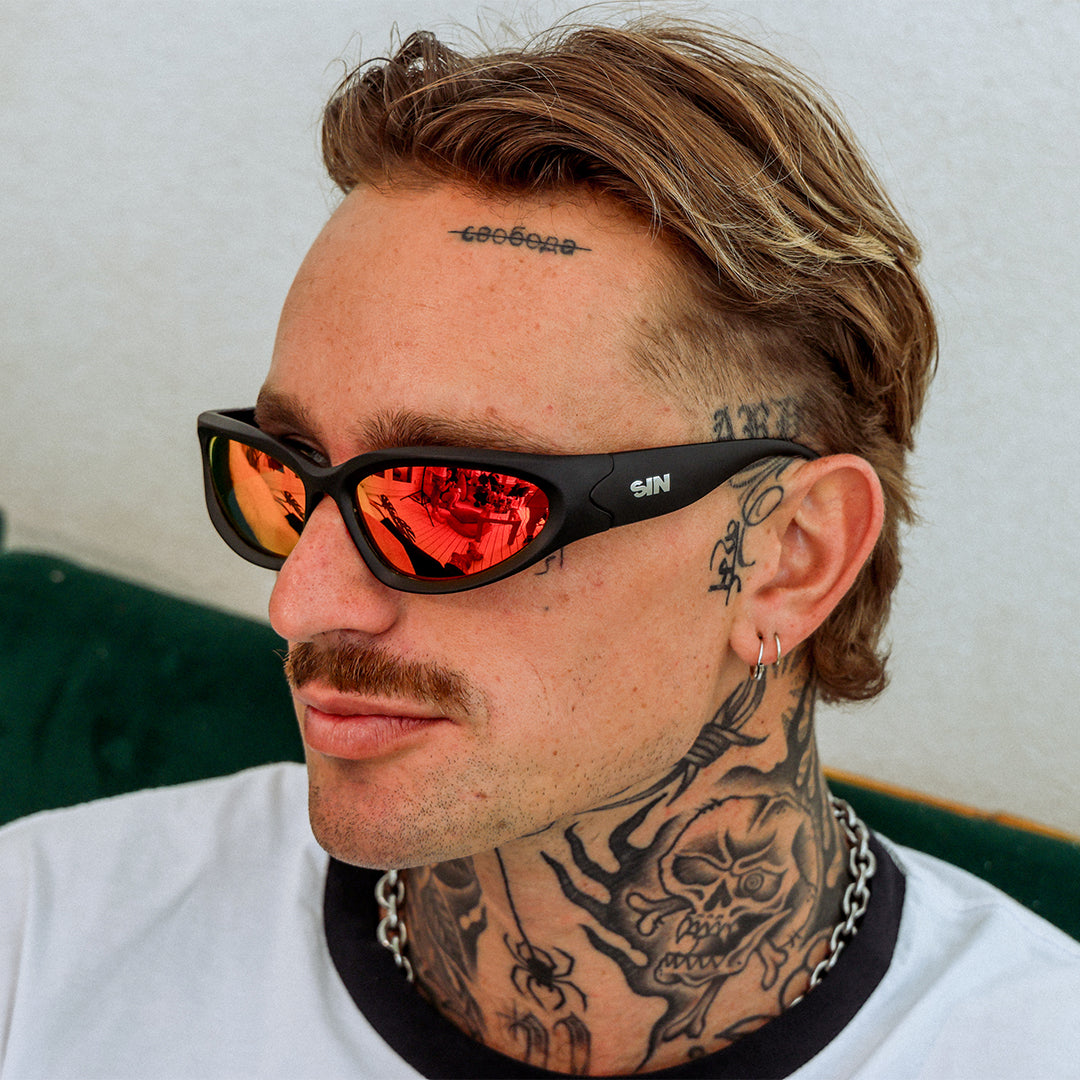 Reefer Polarised Black and Red Wrap Around Sunglasses made of recycled plastic close up on male model looking away from the camera