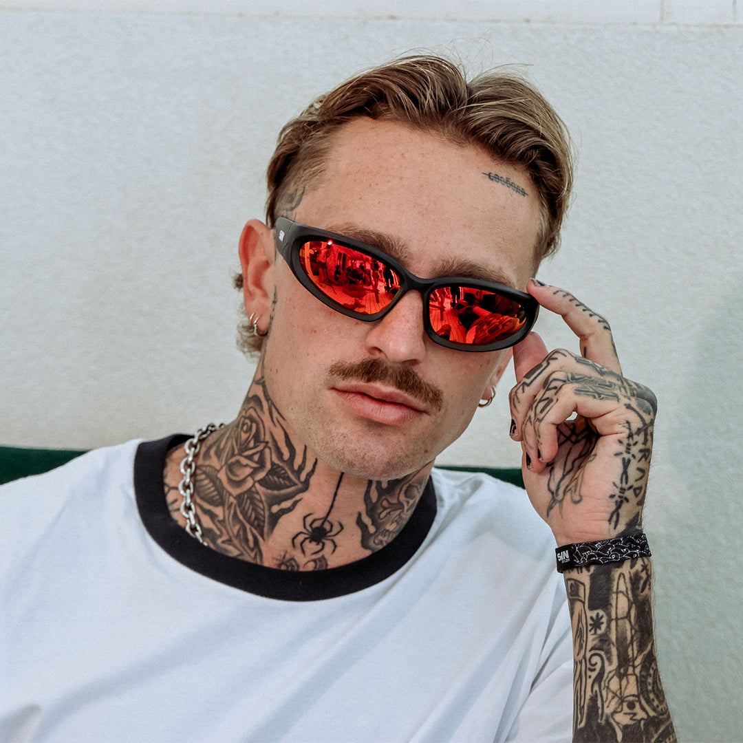 Reefer Polarised Black and Red Wrap Around Sunglasses made of recycled plastic on male model looking towards the camera
