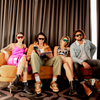 LOOSE CANNON Polarised Pink Shield Square Sunglasses on a female model sitting on a couch with other models