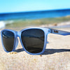 The Game Changer Polarised Square Sunglasses with Blue Frame on beach sand