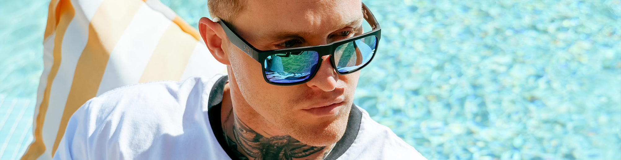 male model wearing blue sunglasses by the pool