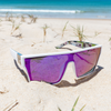 LOOSE CANNON Polarised White Shield Square Sunglasses with Purple Mirrored Lens on the beach