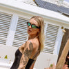 Reefer Polarised Black and Green Wrap Around Sunglasses made of recycled plastic on female model looking back at camera