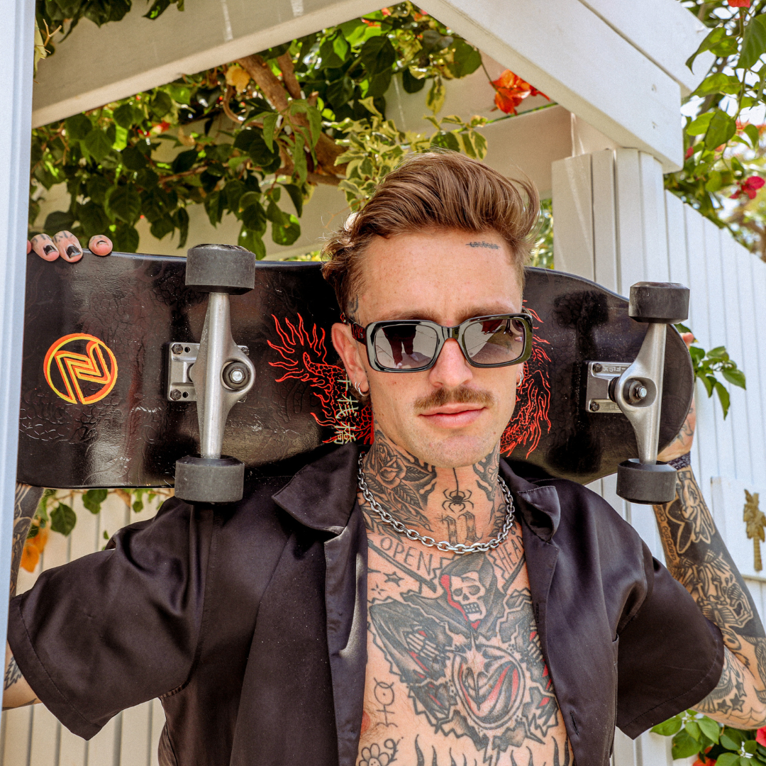 Rocker Polarised Black Rectangle Sunglasses on a male model holding a skateboard