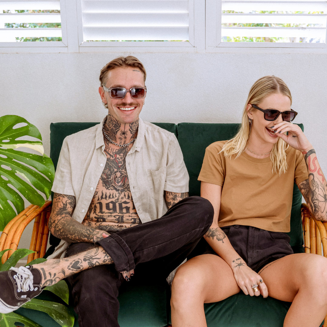 Rocker Polarised Grey Rectangle Sunglasses on a male model sitting on a couch and smiling