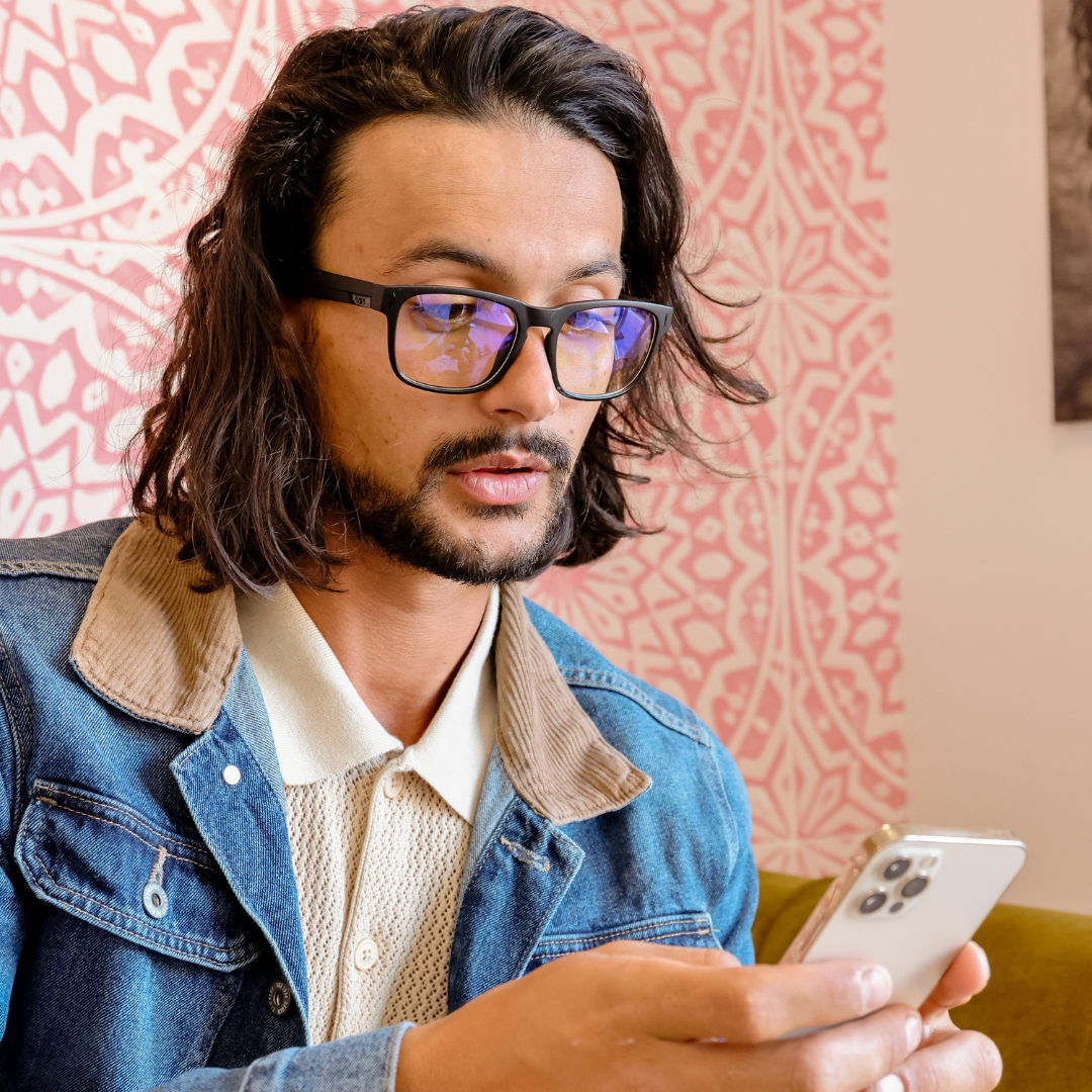 Spartan Black Rectangle Blue Light Glasses on a male model looking at his phone screen