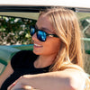 Spartan Recycled Rectangle Sunglasses with Black Frame and Blue Matte lens on a female surfer