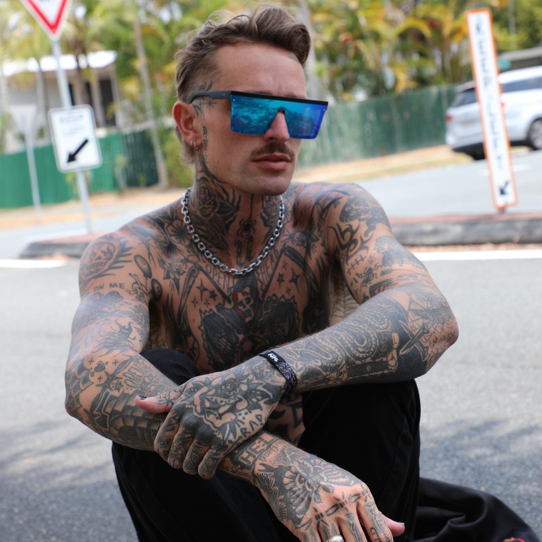 THE BAR Black Polarised Blue Square Sunglasses on a male model sitting on a skateboard