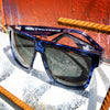 Vespa II Polarised Square Sunglasses with Blue Frame near a wall